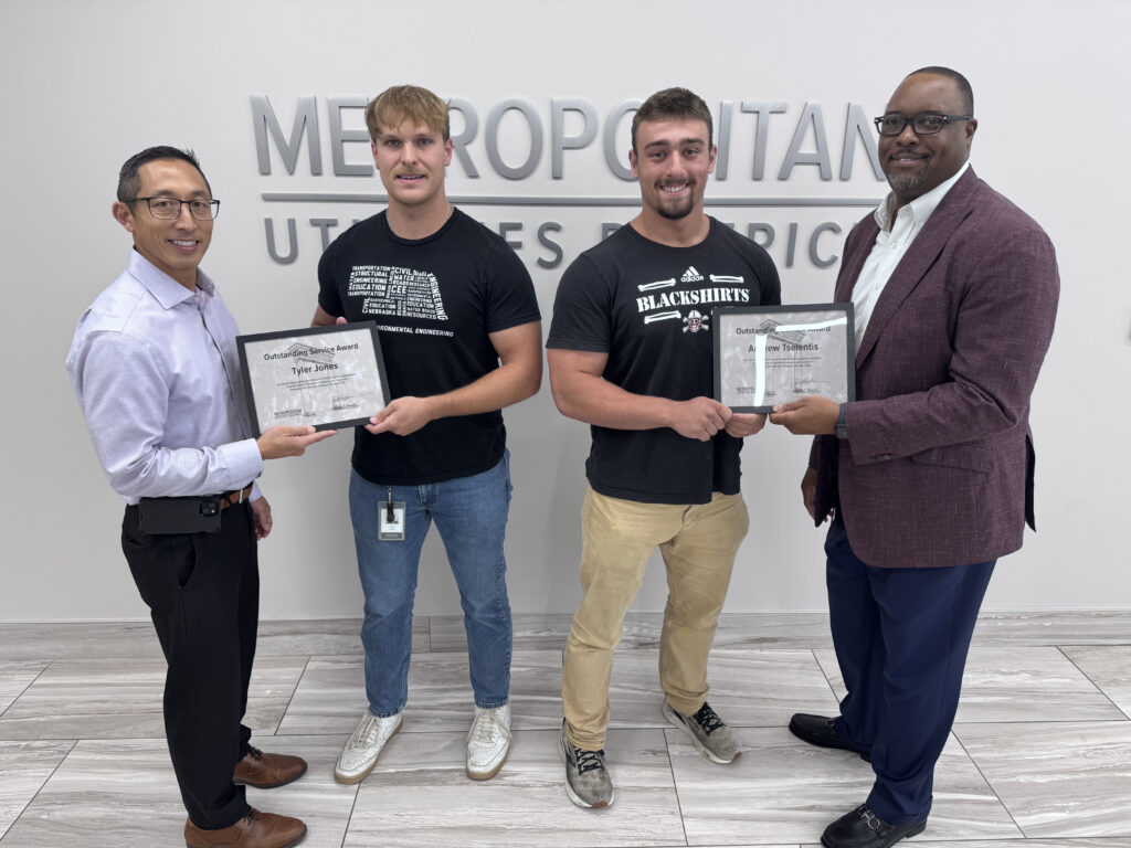 Two summer hires smile as they are presented with the District's Outstanding Service Award by their superiors