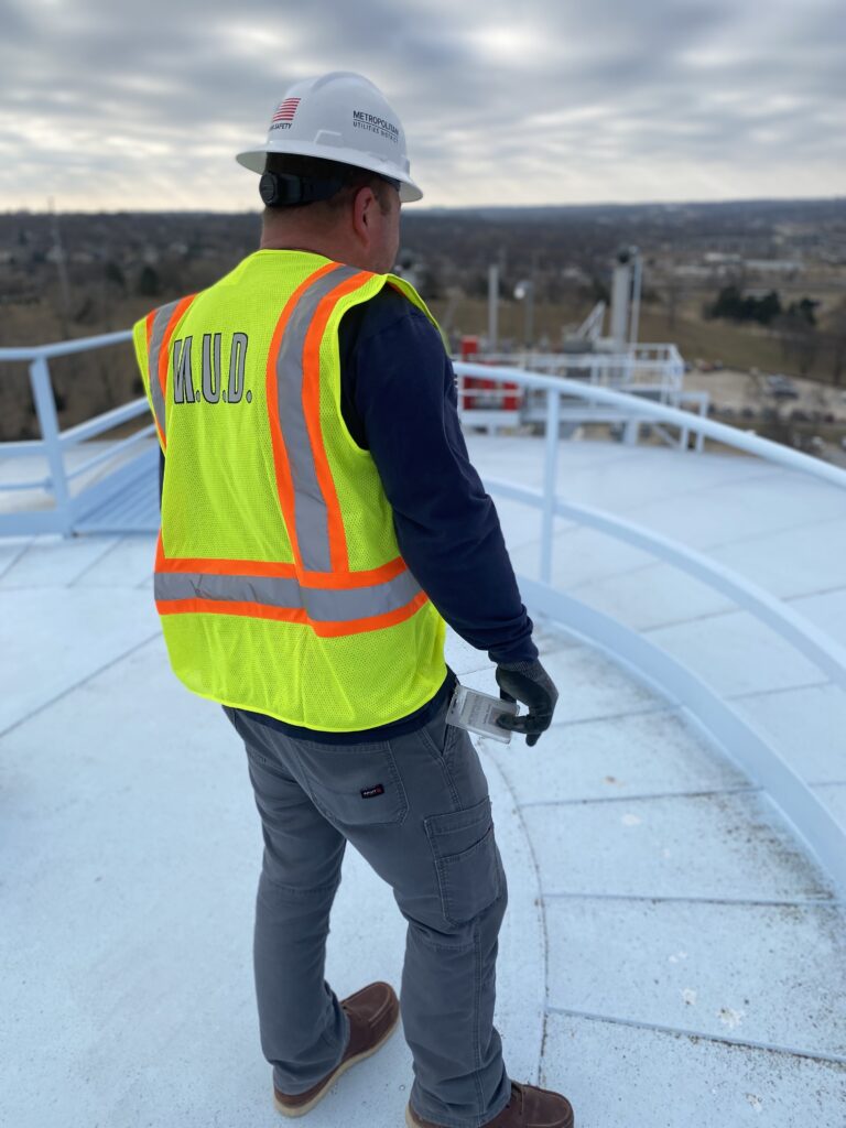 Utility worker conducts an inspection from the top of a utility storage tank